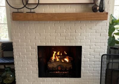 vented gas logs in white brick fireplace