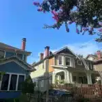 A blue house surrounded by a picket fence and a matching blue picket fence in the front yard.