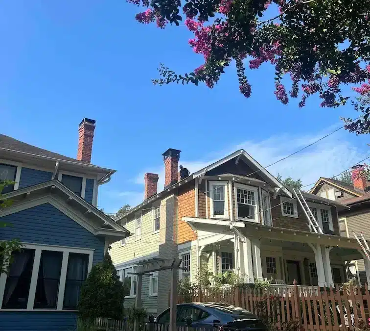 A blue house surrounded by a picket fence and a matching blue picket fence in the front yard.